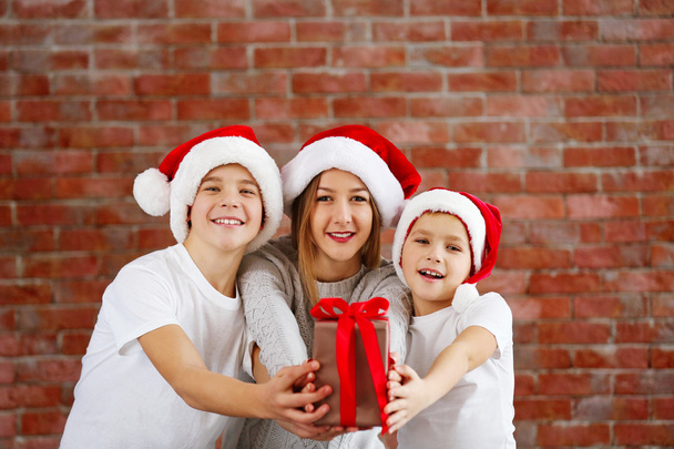 Happy cousins with gift box on brick wall background - Фото, изображение