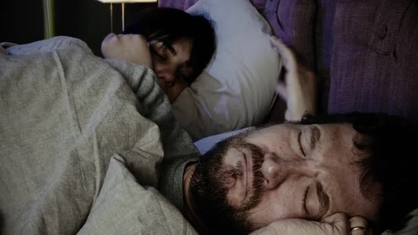 Sad man crying in bed while girlfriend is sleeping at night - Video, Çekim