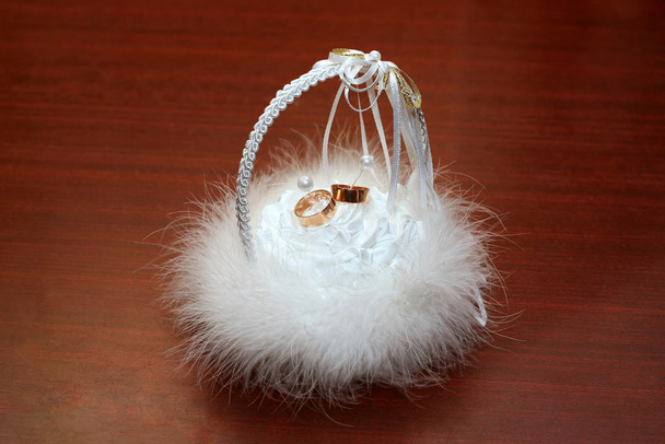 Wedding rings laying in a white fluffy basket - Фото, зображення