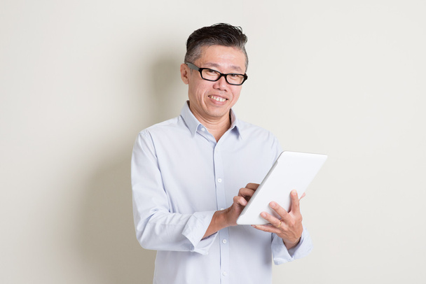 Mature Asian man using tablet pc - Foto, Bild