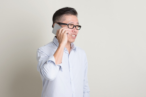 Mature Asian man making call on smartphone - Valokuva, kuva