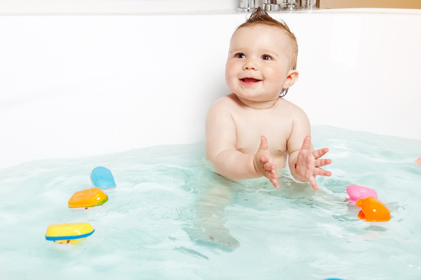 Aranyos baba taps kezét és mosolyogva, miközben fürdik - Fotó, kép