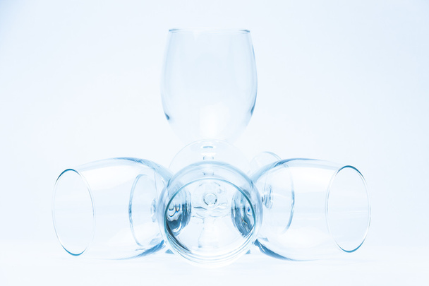 Wine glasses stand and lie symmetrically on white - Foto, Imagen
