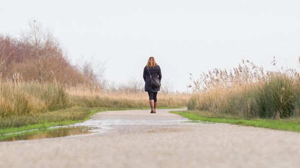 Νεαρή γυναίκα το περπάτημα σε ένα ολλανδικό τοπίο - Φωτογραφία, εικόνα