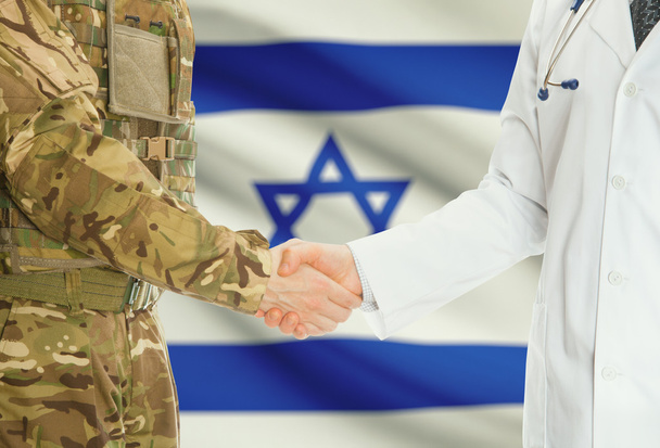 Military man in uniform and doctor shaking hands with national flag on background - Israel - 写真・画像