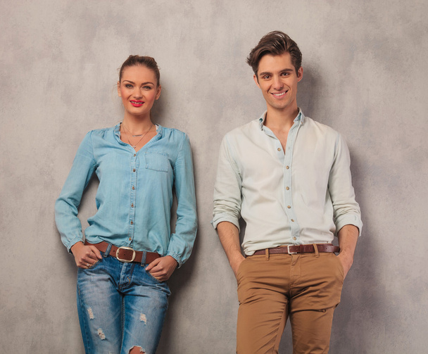 smiling couple leaning against the wall with hands in pockets - Foto, Bild