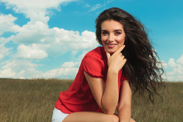 bruneta se usmívá na kameru při posezení v polích  - Fotografie, Obrázek