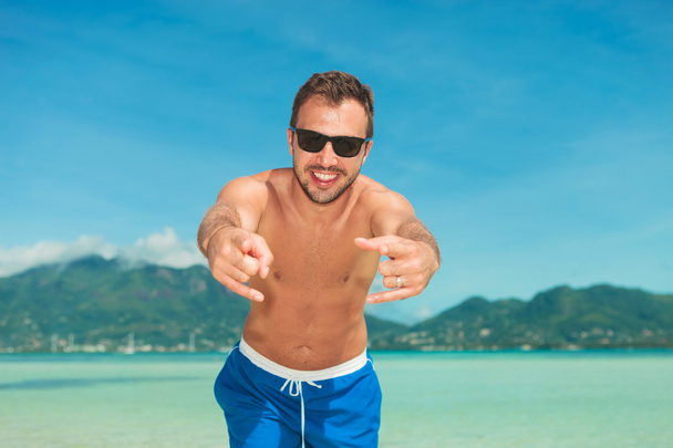 muž na pláži s úsměvem a poiting na na kameru - Fotografie, Obrázek