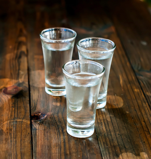 Cold vodka in a glass on a wooden table - Фото, зображення