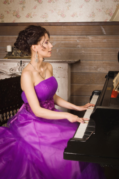 Woman dressed in long lace dress playing piano - 写真・画像
