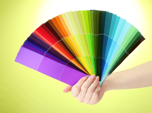 Hand holding bright palette of colors on green background - Photo, Image