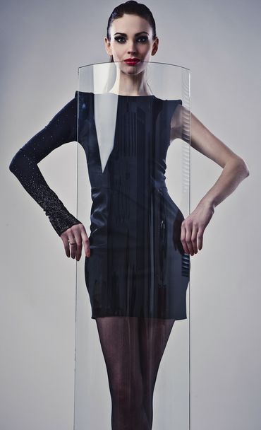 Young beautiful brunette pose in a fashionable dress near decorative glass. - Foto, Bild