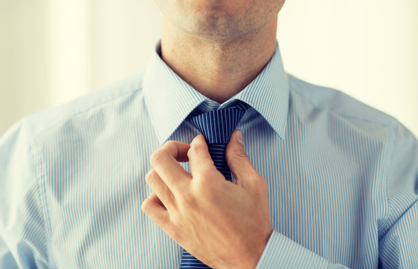 close up of man in shirt adjusting tie on neck - Foto, afbeelding