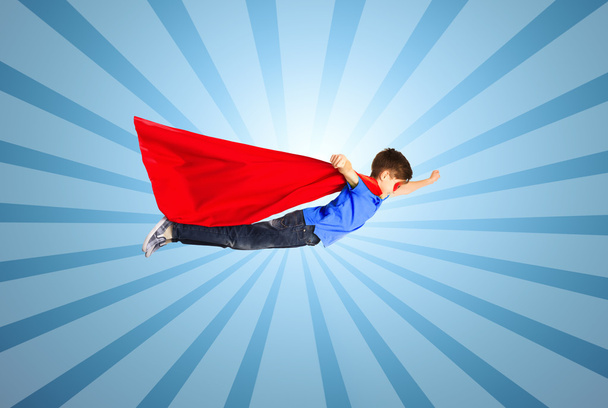 niño en capa de superhéroe rojo y máscara volando en el aire
 - Foto, Imagen