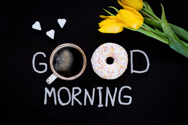 Good morning food: glazed donut, cup of black coffee and yellow tulips - Photo, Image