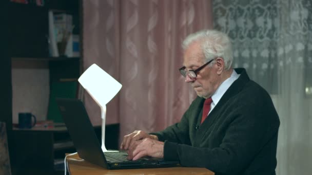Ο παππούς χρησιμοποιεί ένα φορητό υπολογιστή στο σπίτι. - Πλάνα, βίντεο