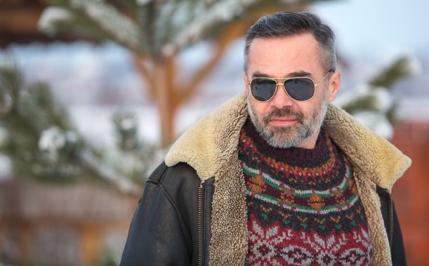 Elegant  handsome man wearing glasses and sweater over winter snowy scenery - Foto, afbeelding