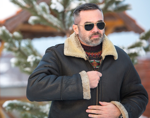 Elegant  handsome man wearing glasses and winter warm clothes over winter scenery - Φωτογραφία, εικόνα