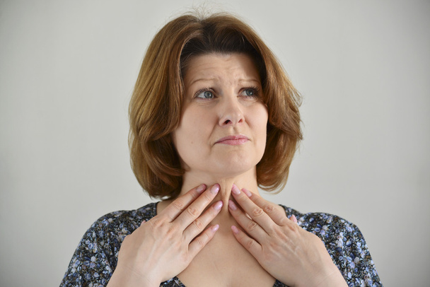 Adult woman with a sore throat on  light background - Foto, afbeelding