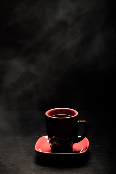 A cup of coffee with smoke on black background. Toned - Foto, Imagem