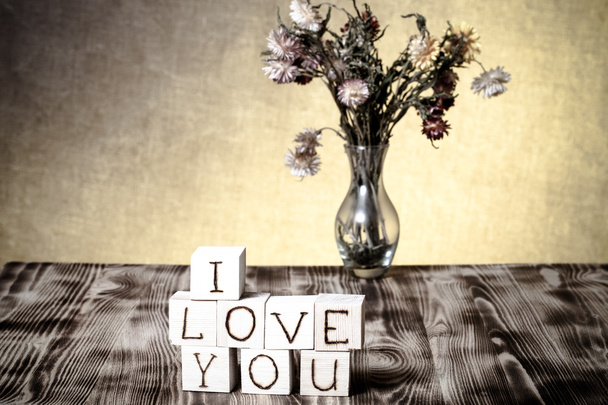 Wooden cubes with inscription "I LOVE YOU" and bouquet of dry fl - Foto, Bild