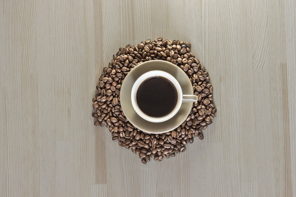 Filiżanka kawy z ziaren kawy na drewnianym stołem.  - Zdjęcie, obraz