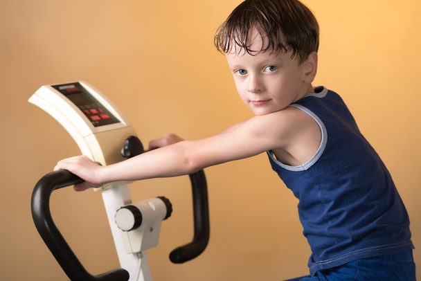 The child is trained on a stationary bike . Healthy lifestyle. - Foto, imagen