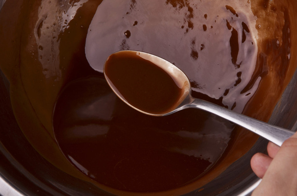 připravuje horkou čokoládu v hrnci na dřevěný stůl přehlédnout shot - Fotografie, Obrázek