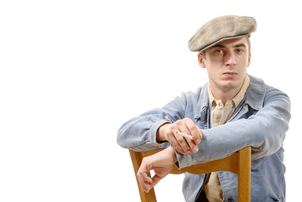 νέος εργαζόμενος σε vintage ρούχα, κάθεται σε μια καρέκλα πάνω σε άσπρο - Φωτογραφία, εικόνα
