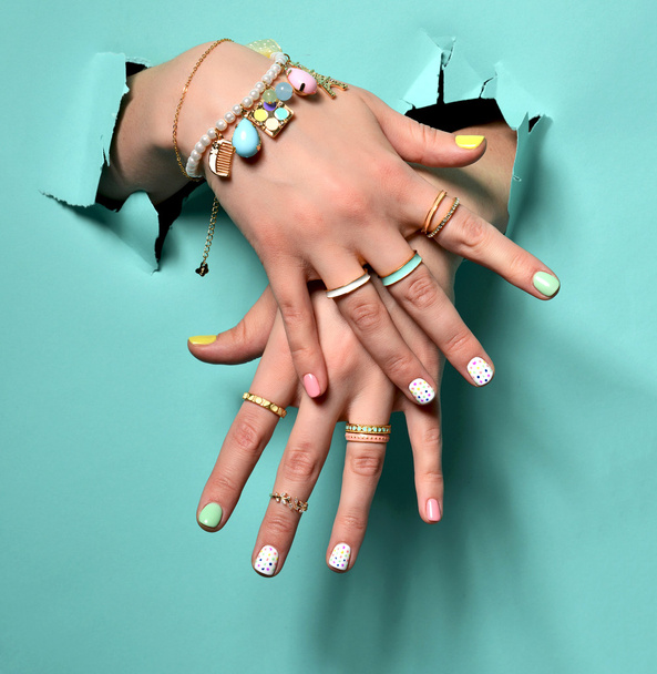 Beautiful woman hands with yellow pink white pattern nail polish - Fotó, kép