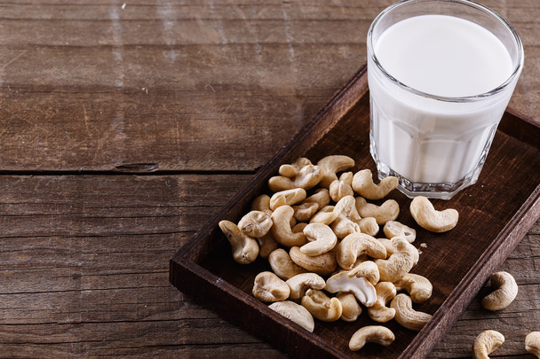 Cashew melk over rustieke houten achtergrond - Foto, afbeelding
