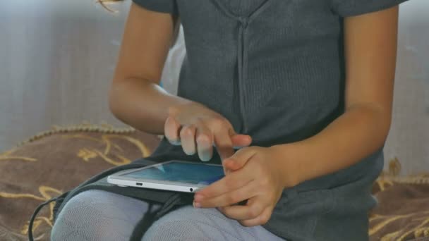 ragazza seduta a giocare in tablet in casa
 - Filmati, video