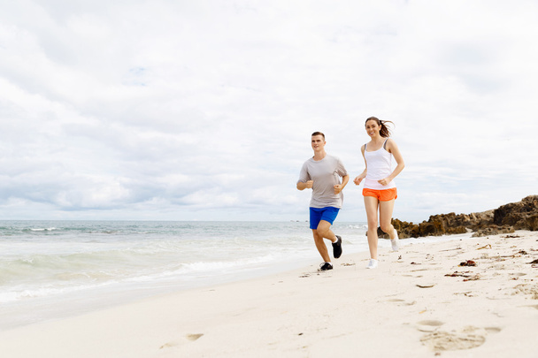 Runners. Young couple running on beach - Photo, Image