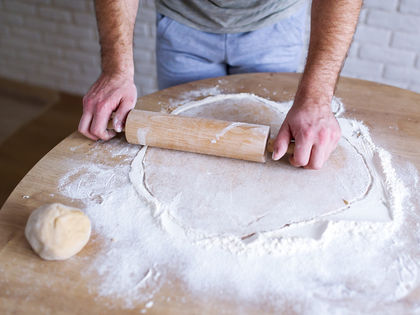 Le cuisinier mâle roule la pâte sur une table
. - Photo, image