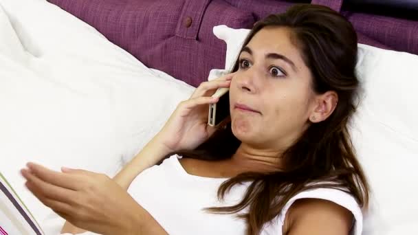 Mujer joven enojada peleando por teléfono acostada en la cama, tiro mediano - Imágenes, Vídeo
