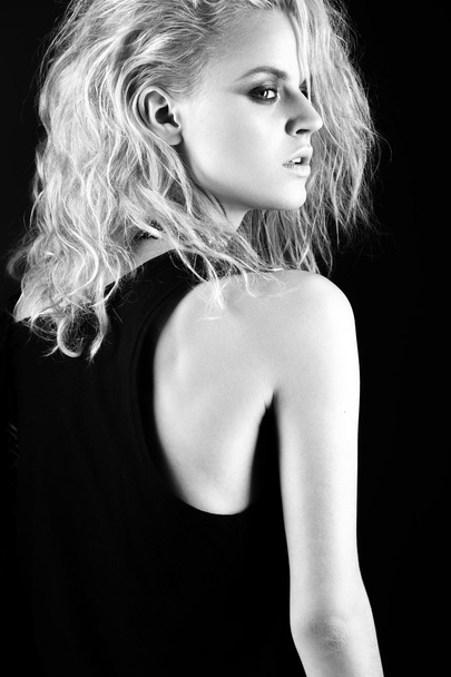 Daring girl model in black leather dress, style of rock, dark make-up, wet hair and bracelets on her arms. - Foto, imagen