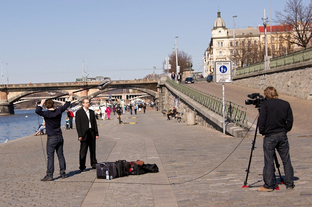Kolmen jäsenen tv-henkilökunta kuvaamassa Prahassa Vltava-joen rannalla
 - Valokuva, kuva