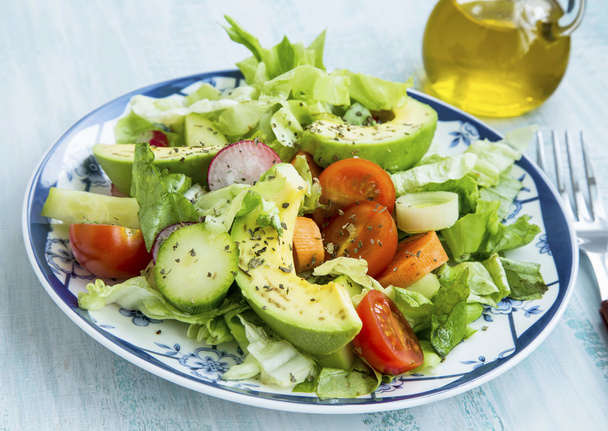 Salade met avocado, sla, tomaten, radijs, uien en specerijen - Foto, afbeelding