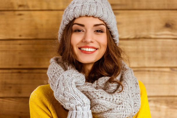 Portrait of a beautiful young girl with hat and gloves on the background of wooden wall - Foto, Imagen