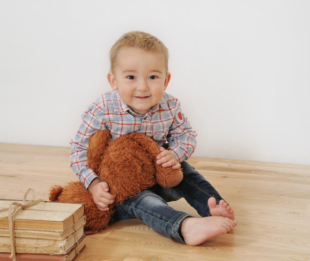 студийный снимок маленького милого улыбающегося мальчика с его игрушкой и книгами
 - Фото, изображение