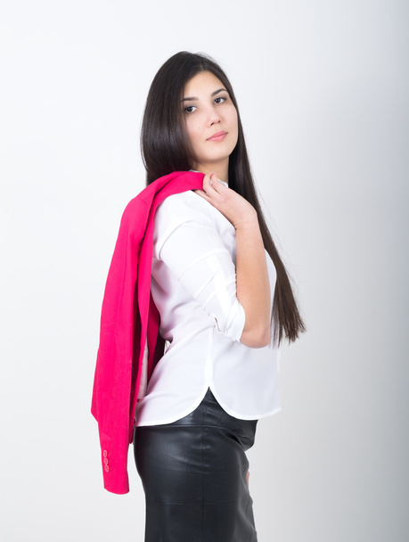 A young pretty slim asian woman standing in a leather skirt and white blouse. holding a red jacket on shoulderl - Photo, image