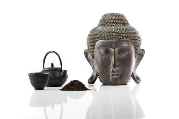 Boeddha hoofd, theepot en kopje thee op een witte achtergrond - Foto, afbeelding
