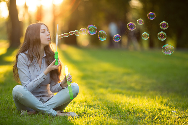 Young spring fashion casual woman blow bubbles in the sunset in  - Foto, Bild