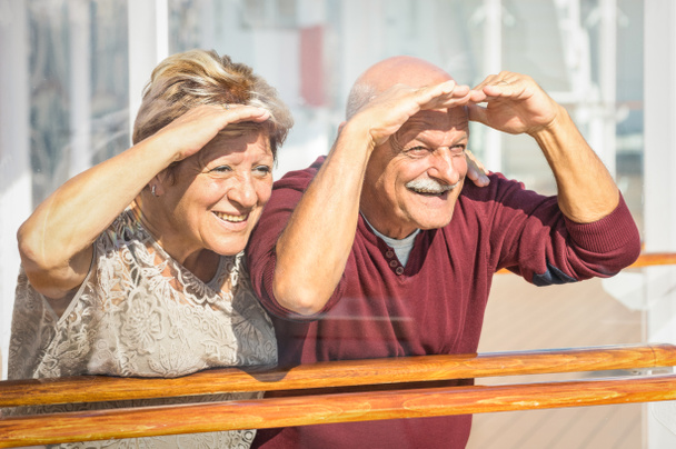 Heureux couple de personnes âgées ayant du plaisir à regarder vers l'avenir - Concept de personnes âgées actives ludiques pendant la retraite - Mode de vie de voyage avec une attitude drôle enfantine - Ton de couleur Marsala avec des reflets en verre doux
 - Photo, image