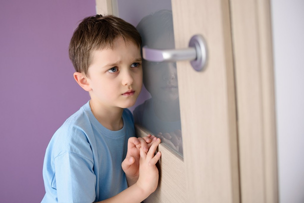 Verdrietig, bang kind luisteren naar een bovenliggende praten via de deur - Foto, afbeelding