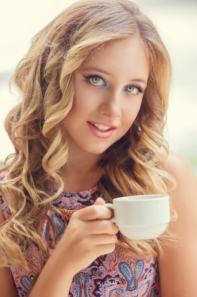 A lovely young girl with blond hair eating dessert and drinking  - Foto, immagini