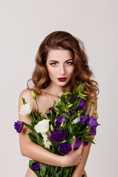 fashion studio photo of beautiful brunette woman with bright makeup with a bouquet of purple and white eustoma - Fotoğraf, Görsel