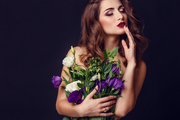 fashion studio photo of beautiful brunette woman with bright makeup with a bouquet of purple and white eustoma - Fotografie, Obrázek