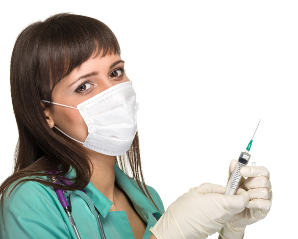 Doctor or nurse in face mask and lab coat holding syringe. Isolated over white. - Fotó, kép