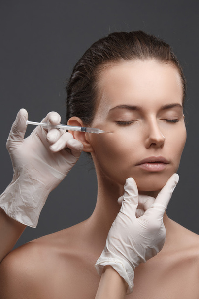 Portrait of young Caucasian woman getting cosmetic injection - Foto, afbeelding